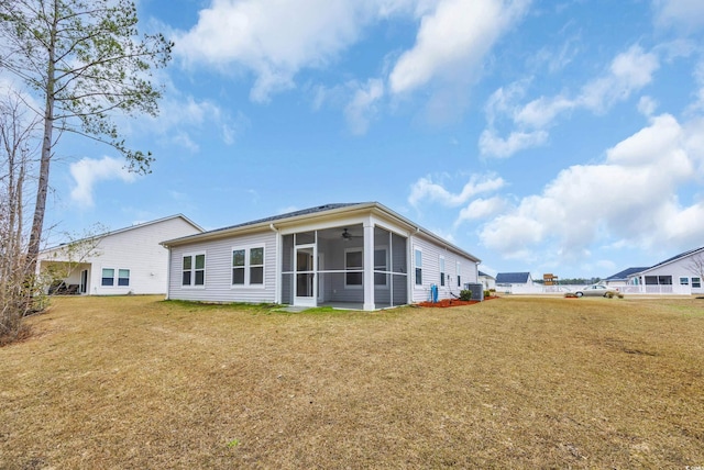 rear view of house featuring a yard and a sunroom