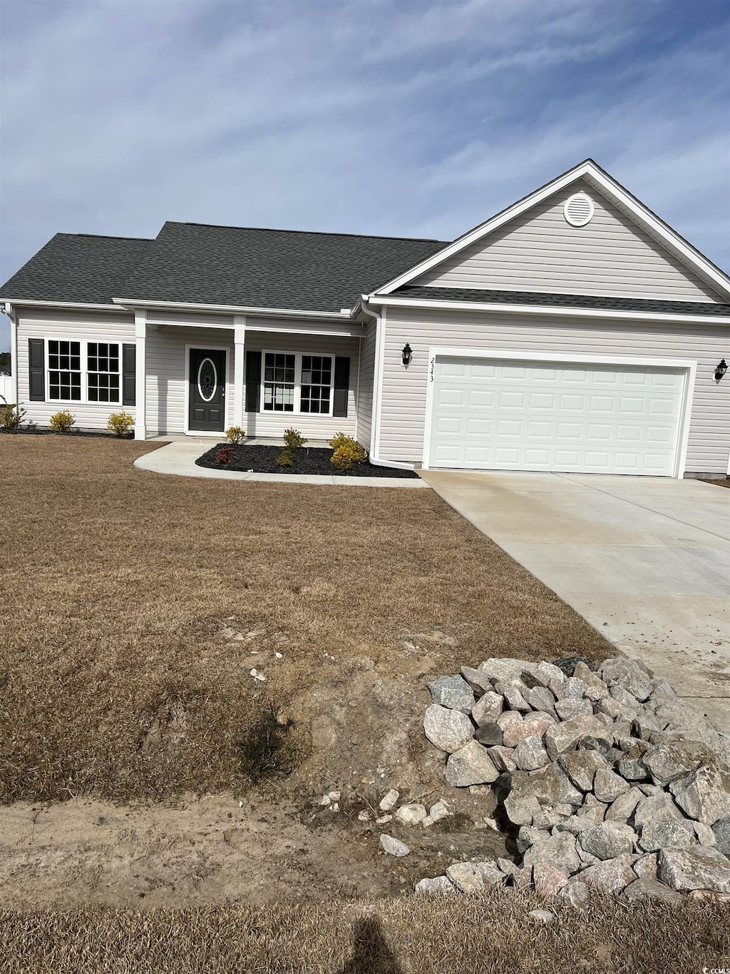 ranch-style home featuring a porch, a garage, driveway, roof with shingles, and a front lawn