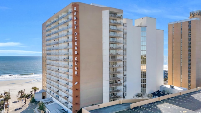 view of building exterior featuring a water view and a view of the beach