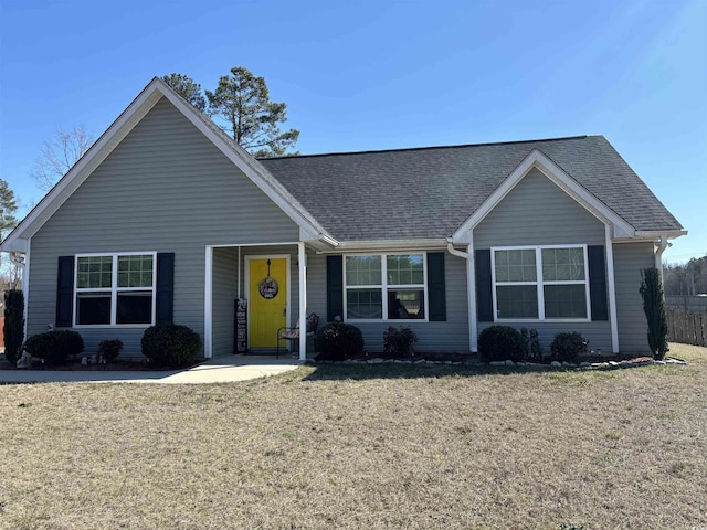 ranch-style home with a shingled roof and a front yard