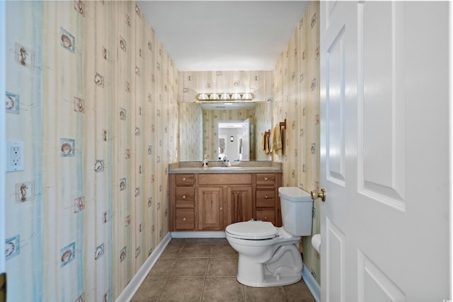 bathroom featuring wallpapered walls, baseboards, toilet, tile patterned floors, and vanity