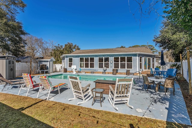 back of property featuring entry steps, a fenced backyard, a fenced in pool, and an outbuilding