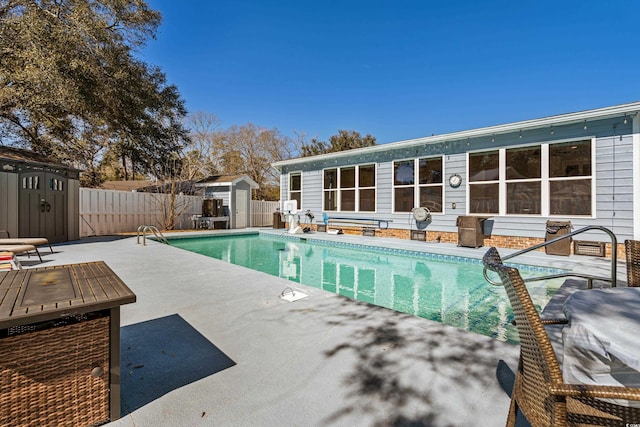 view of swimming pool with an outbuilding, a fenced backyard, and a storage unit