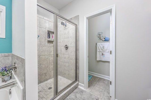 full bathroom with marble finish floor, a shower stall, and baseboards