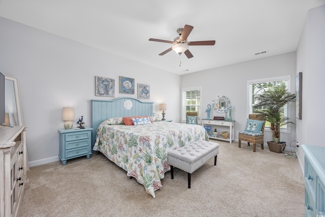 bedroom with a ceiling fan, light colored carpet, visible vents, and baseboards