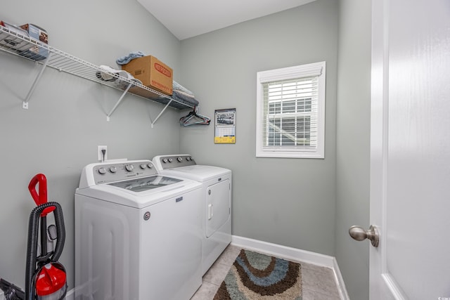 clothes washing area featuring laundry area, baseboards, washer and dryer, and light tile patterned flooring