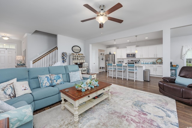 living area featuring stairs, ceiling fan, and dark wood-style flooring