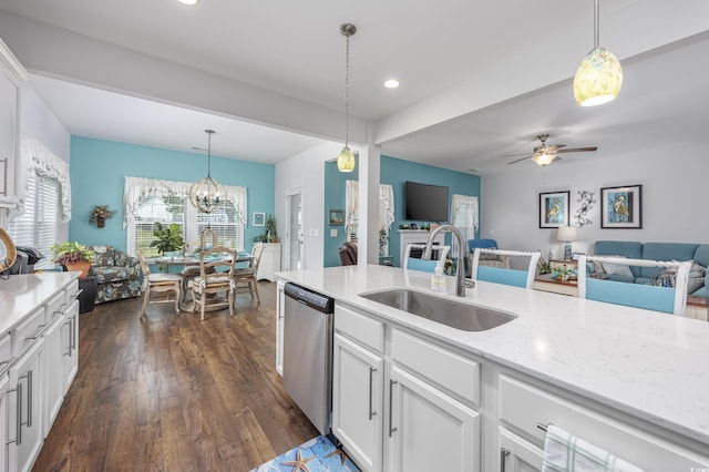 kitchen featuring pendant lighting, open floor plan, white cabinetry, a sink, and dishwasher