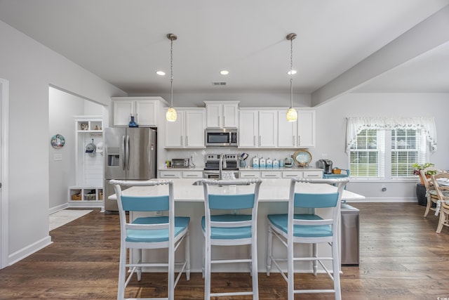 kitchen featuring stainless steel appliances, hanging light fixtures, a center island with sink, and white cabinetry