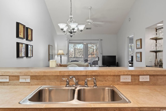 kitchen with lofted ceiling, visible vents, hanging light fixtures, open floor plan, and a sink