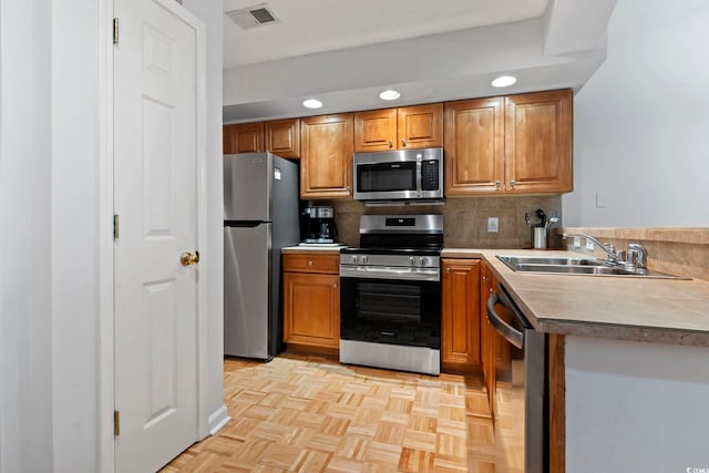 kitchen featuring stainless steel appliances, a sink, visible vents, backsplash, and brown cabinets