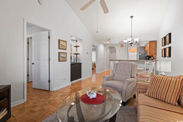 living area featuring high vaulted ceiling, arched walkways, baseboards, and ceiling fan with notable chandelier