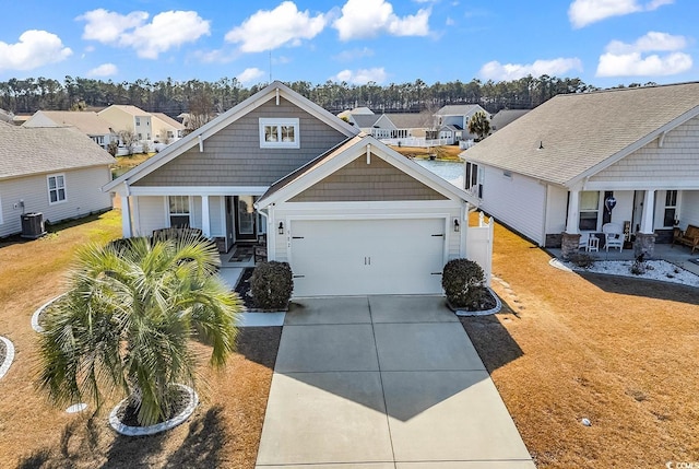 view of front of house featuring a residential view, concrete driveway, covered porch, and central AC unit