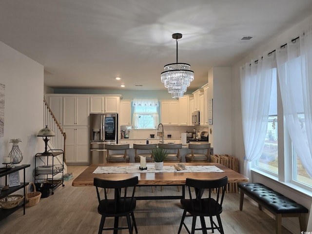 dining area featuring a chandelier, light wood finished floors, stairway, and recessed lighting