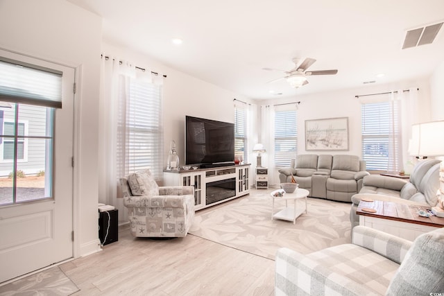 living area with light wood-style floors, a healthy amount of sunlight, and visible vents