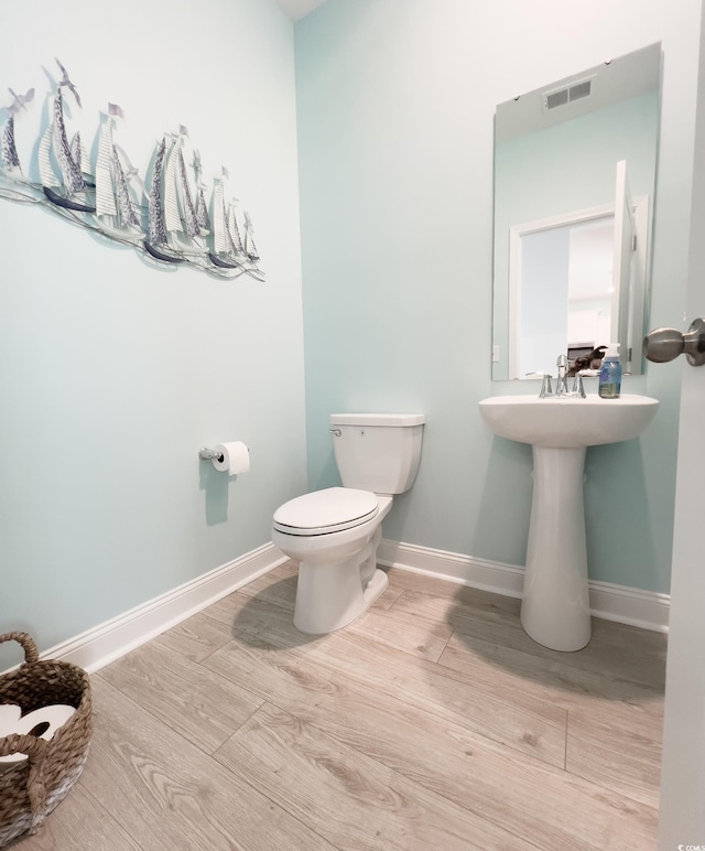 bathroom with toilet, baseboards, visible vents, and wood finished floors