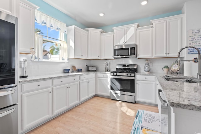 2476 Blue Crane Cir Unit 101, Myrtle Beach, SC 29577 - kitchen featuring white cabinets, light wood-type flooring, appliances with stainless steel finishes, and decorative backsplash