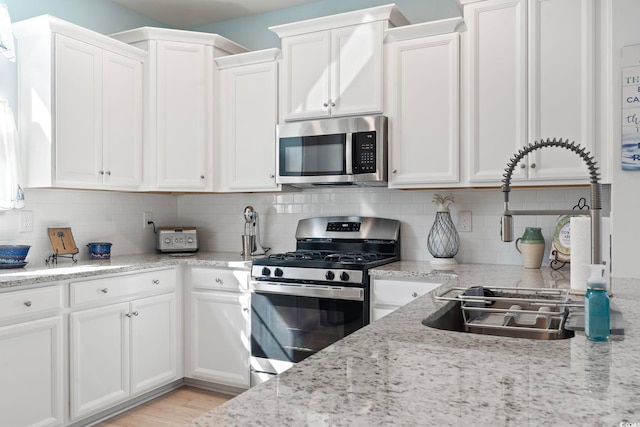 2476 Blue Crane Cir Unit 101, Myrtle Beach, SC 29577 - kitchen with white cabinets, a sink, light stone countertops, tasteful backsplash, and appliances with stainless steel finishes