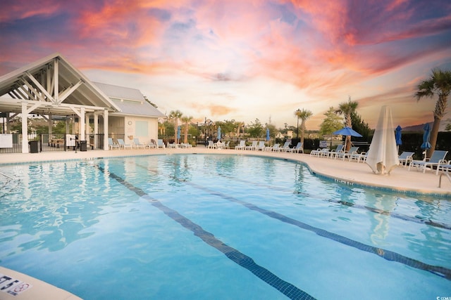 2476 Blue Crane Cir Unit 101, Myrtle Beach, SC 29577 - pool at dusk featuring a community pool, fence, and a patio