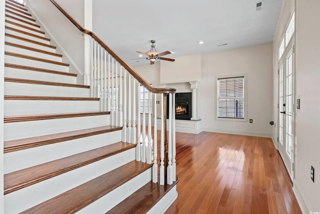 entryway featuring a ceiling fan, hardwood / wood-style floors, stairway, baseboards, and visible vents