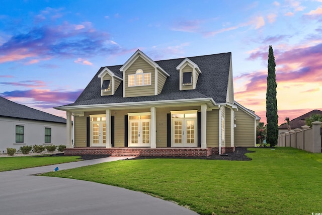 view of front of property with french doors, roof with shingles, fence, and a front lawn