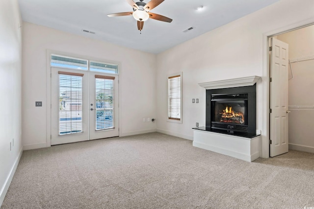 unfurnished living room with baseboards, visible vents, french doors, and light colored carpet