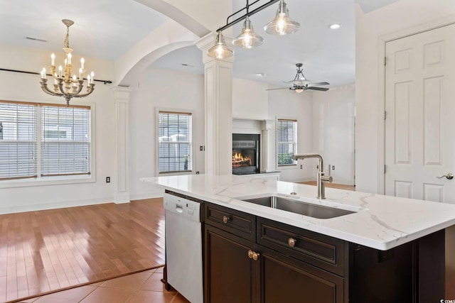 kitchen with a sink, a center island with sink, dishwasher, and hanging light fixtures