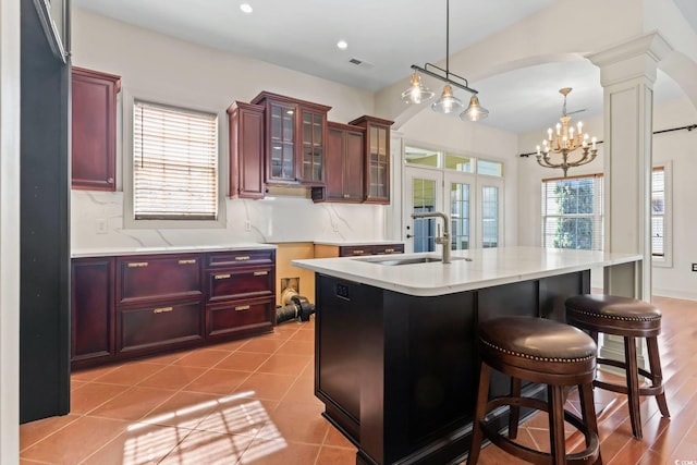 kitchen featuring dark brown cabinets, glass insert cabinets, light countertops, and a sink