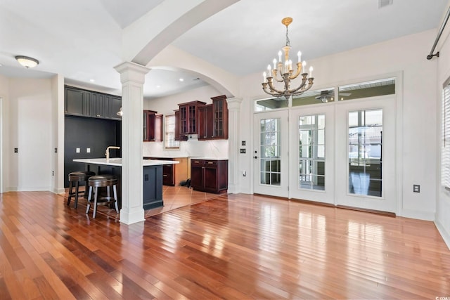 interior space featuring an inviting chandelier, light wood-style flooring, baseboards, arched walkways, and recessed lighting