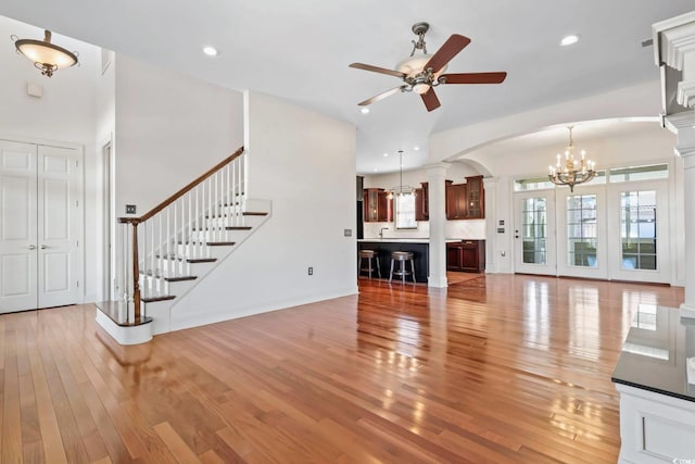 unfurnished living room featuring ceiling fan with notable chandelier, stairway, recessed lighting, and wood finished floors