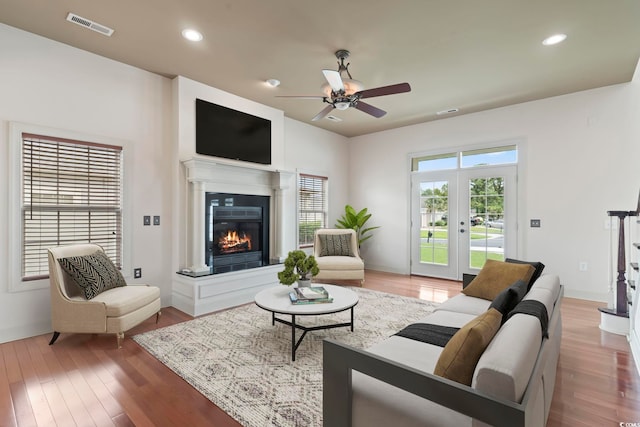 living room featuring a ceiling fan, recessed lighting, a glass covered fireplace, visible vents, and wood finished floors