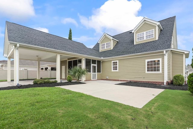 rear view of property with a yard, roof with shingles, and a patio area