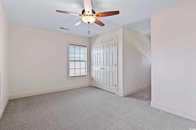 unfurnished bedroom with a closet, light colored carpet, visible vents, a ceiling fan, and baseboards