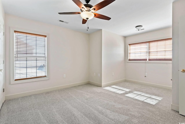 unfurnished room featuring light carpet, ceiling fan, visible vents, and baseboards