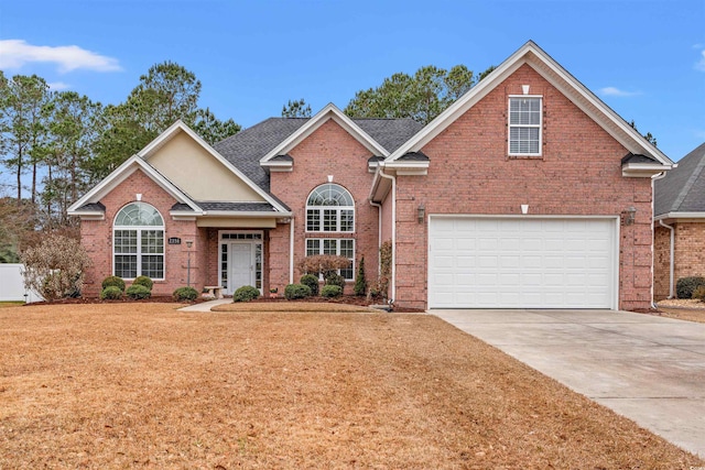 traditional-style home with a garage, brick siding, a shingled roof, concrete driveway, and a front yard