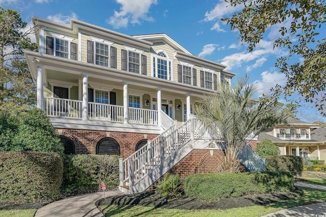 view of front facade featuring stairs, a porch, and brick siding