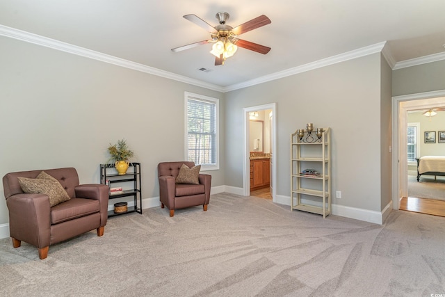 living area with light carpet, visible vents, baseboards, a ceiling fan, and ornamental molding