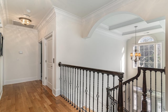 hallway featuring baseboards, visible vents, wood finished floors, beamed ceiling, and an inviting chandelier