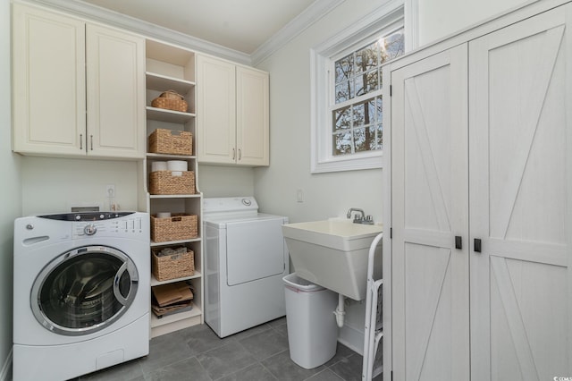 washroom featuring ornamental molding, washing machine and dryer, cabinet space, and dark tile patterned flooring