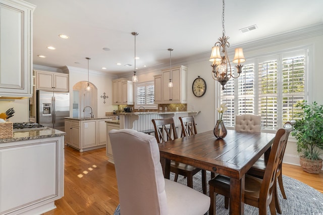 dining room with light wood-style floors, visible vents, a chandelier, and crown molding