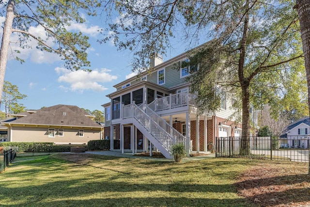 back of property featuring stairs, brick siding, a lawn, and a sunroom