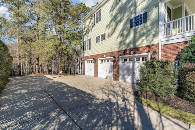 view of property exterior featuring brick siding, driveway, and an attached garage