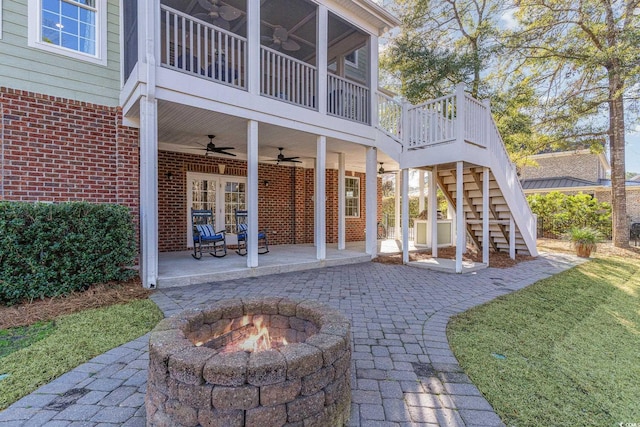 back of property with brick siding, a patio, stairway, a ceiling fan, and a fire pit