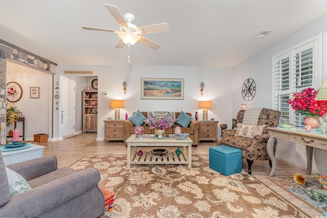 living area with baseboards, ceiling fan, visible vents, and wood finished floors