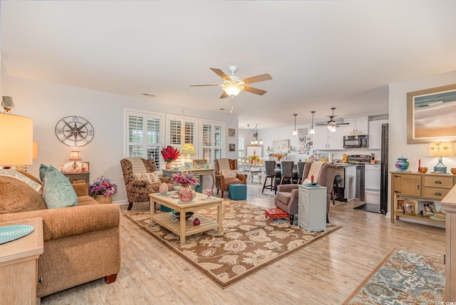 living area featuring light wood-style floors, visible vents, and ceiling fan