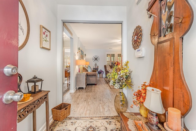 hall featuring light wood-style flooring and baseboards