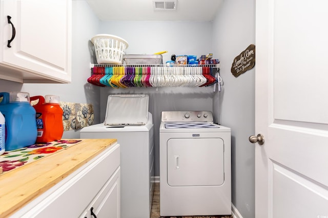 clothes washing area featuring independent washer and dryer, cabinet space, and visible vents