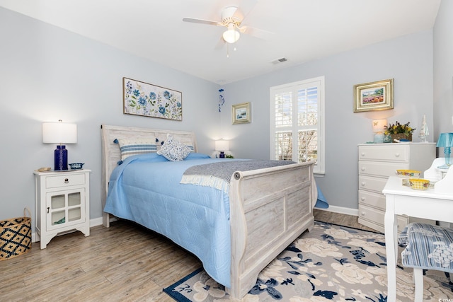 bedroom featuring baseboards, a ceiling fan, visible vents, and light wood-style floors