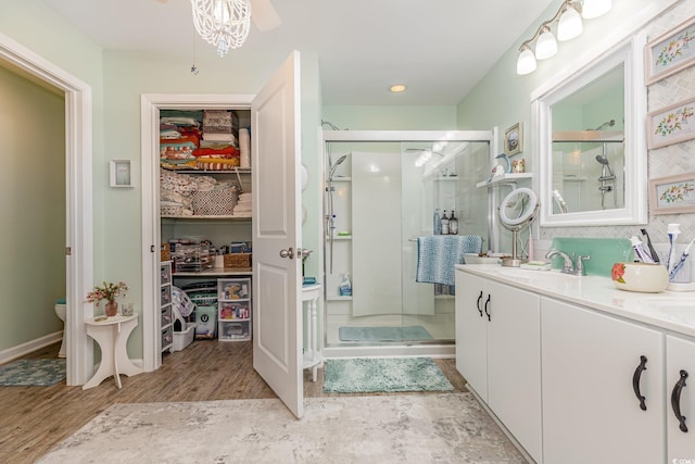 bathroom with decorative backsplash, toilet, wood finished floors, vanity, and a shower stall