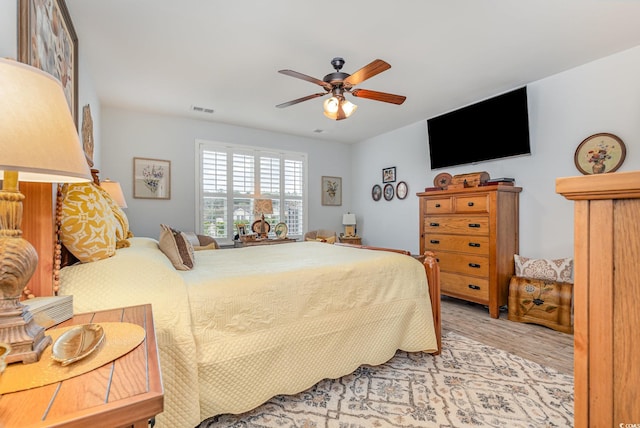 bedroom with light wood-type flooring, visible vents, and ceiling fan